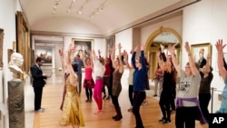 FILE - An exercise group works in front of a bust of Benjamin Franklin at the Metropolitan Museum of Art in New York, Feb. 10, 2017.