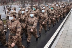 In this Jan. 26, 2020, photo released by Xinhua News Agency, members of a military medical team head for Wuhan Jinyintan Hospital in Wuhan, central China's Hubei province. (Cheng Min/Xinhua via AP)