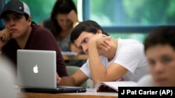 In this Sept. 9, 2013 photo, University of Miami student Gabriel Dias studies the daily lesson plan on his computer during a Spanish language class in Coral Gables, Fla.