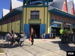 Customers sit outside the Caribbean Marketplace in Little Haiti, Miami, Florida. (Photo: S. Lemaire / VOA)