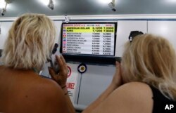 Turkish citizens look at a board showing foreign currency rates inside a currency exchange shop in Ankara, Turkey, Aug. 10, 2018.