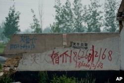 In this April 29, 2019 photo, graffiti advertising a marriage agent is spray-painted on the wall of a warehouse in Pei County in eastern China's Jiangsu province.