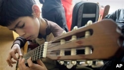 An Afghan student practices playing the guitar in a class.