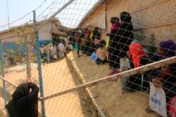 In this file photo taken on March 24, 2020, Rohingya refugees, without wearing any facemask or any other safty gear as a preventive measure against the COVID-19 novel coronavirus, wait in a relief distribution point at Kutupalong refugee camp.