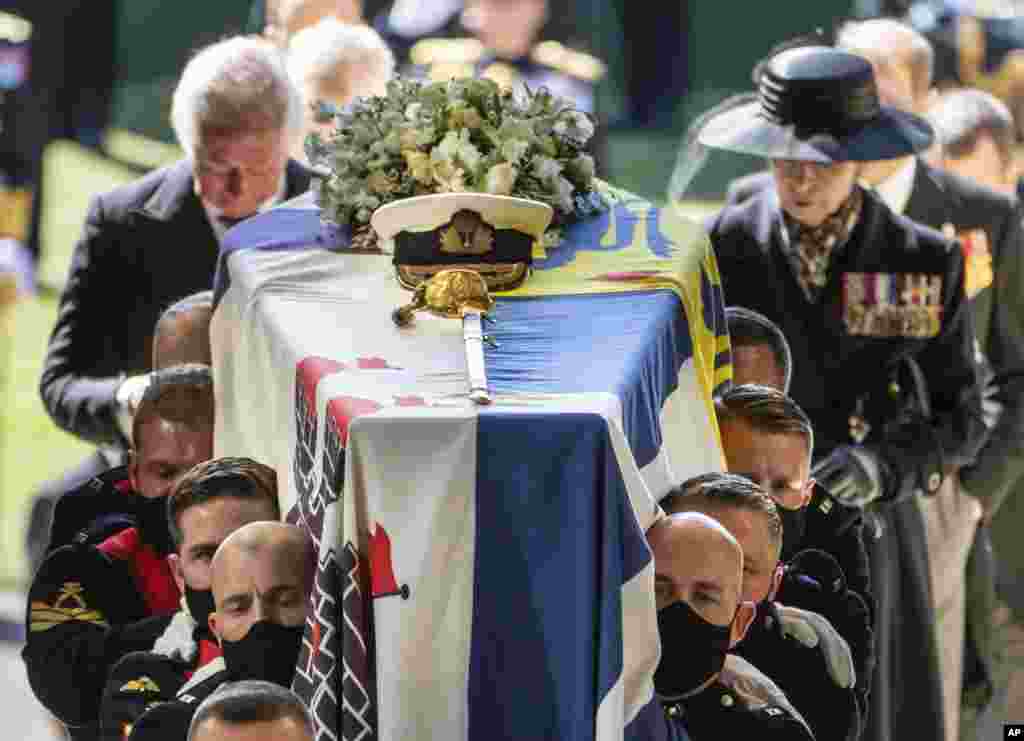 Pall bearers carrying the coffin of the Duke of Edinburgh, followed by the Prince of Wales, left and Princess Anne, right, into St. George's Chapel for his funeral, at Windsor Castle, in Windsor, England, April 17, 2021.