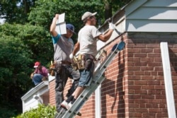 These workers repair the roof of a house in the U.S. state of Virginia, June 2014. (AP Photo/J. Scott Applewhite)
