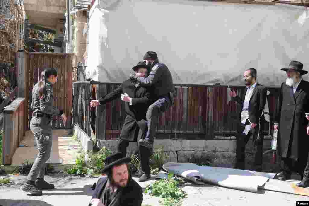 A police officer jumps on a demonstrator's back where Ultra-Orthodox Jewish men are demonstrating against joining the army, outside the military recruitment bureau in Jerusalem.