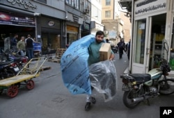 FILE - A man carries car parts at a market in downtown Tehran, Iran, Oct. 9, 2017. Iranians hope lifting of most international sanctions under Tehran’s landmark 2015 nuclear deal with the West would revive their country's long-suffering economy.