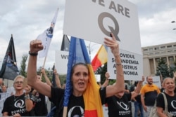 Romanian supporters of QAnon shout slogans against the government's measures to prevent the spread of the COVID-19 infections, like wearing a face mask, during a rally in Bucharest, Romania, Monday, Aug. 10, 2020.(AP/Vadim Ghirda)