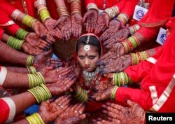 Brides display their hands decorated with henna around a bride as she poses for her own photographer during a mass marriage ceremony in which, according to its organizers, 70 Muslim couples took their wedding vows, in Ahmedabad, India, February 11, 2018.