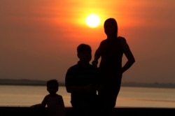 A family takes a photo as the sun rises in Phnom Penh, Cambodia, Friday, Jan. 24, 2020. ((AP Photo/Heng Sinith))