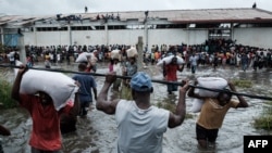 People take sacks of rice from a warehouse surrounded by flood waters from Cyclone Idai, in Beira, Mozambique, March 20, 2019.