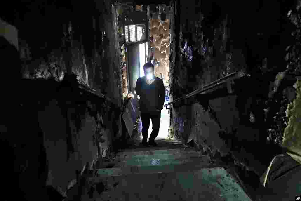 A man lights his mobile phone as he films the burned stairs of Tripoli municipality that was set on fire by protesters during a protest against deteriorating living conditions and strict coronavirus lockdown measures, in Tripoli, Lebanon.