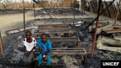 In this photo taken on 3 March 2016 in South Sudan, Chubat (right), 12, sits with her friend in the burned ruins of her school in Malakal Protection of Civilian site. (Hakim George/UNICEF)