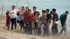 ARCHIVO: Migrantes que cruzaron el Río Grande desde México a EEUU esperan en Eagle Pass, Texas, el 31 de julio de 2023.