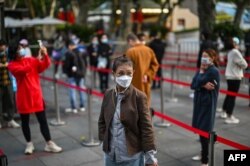 FILE - People wait in line to get tested for the coronavirus, in Jing'an district, Shanghai, China, Oct. 25, 2022. (Photo by Hector RETAMAL / AFP)