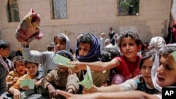 FILE In this April, 13, 2017 file photo, Yemenis present documents in order to receive food rations provided by a local charity, in Sanaa, Yemen.