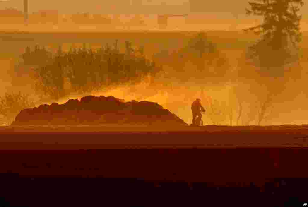 A man rides his bike past a steaming dunghill as the sun rises in Frankfurt, Germany.