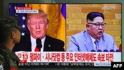 A South Korean soldier walks past a television screen showing pictures of US President Donald Trump (L) and North Korean leader Kim Jong Un at a railway station in Seoul on March 9, 2018.