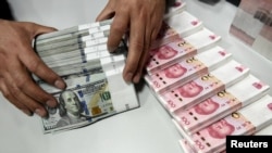 一名中国的银行职员在点数美元和人民币。（资料照片）