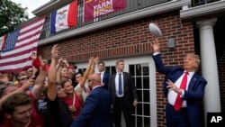 El expresidente Donald Trump lanza una pelota de fútbol americano a la multitud durante una visita a Alpha Gamma Rho, en la Universidad Estatal de Iowa antes de un partido de fútbol americano universitario el 9 de septiembre de 2023, en Ames, Iowa.