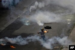 Un manifestante lanza una bomba molotov a la policía que lanzó gases lacrimógenos a una protesta de médicos y estudiantes de medicina que exigían la apertura de un canal humanitario en Caracas.