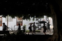 People shelter from volcanic ash under umbrellas as the Cumbre Vieja volcano continues to erupt on the Canary Island of La Palma, in Llanos de Aridane, Spain, October 18, 2021. (REUTERS/Susana Vera)