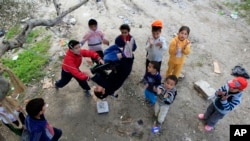 Syrian refugee children, who fled their homes with their families, play on swings, in the southern port city of Sidon, Lebanon. (AP Photo/Mohammed Zaatari, February 2013)
