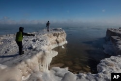 A young boy tosses a chunck of snow into Lake Michigan Wednesday, Jan. 30, 2019 in Milwaukee. Temperatures were sub-zero and wind chills were -50 degrees. (AP Photo/Jeffrey Phelps)