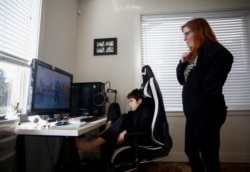 Tracey Pucci and son Foxton Harding, 12, watch an exercise video created by Foxton's teachers at Northshore Middle School as the school district moves to online learning for two weeks because of the new coronavirus, March 11, 2020. (Photo: Reuters / Lindsey Wassen)