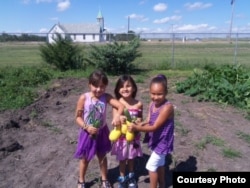 Young members of the Crow Creek community showing the fruits of their gardening labors. Photo courtesy of the Crow Creek Fresh Food Initiative