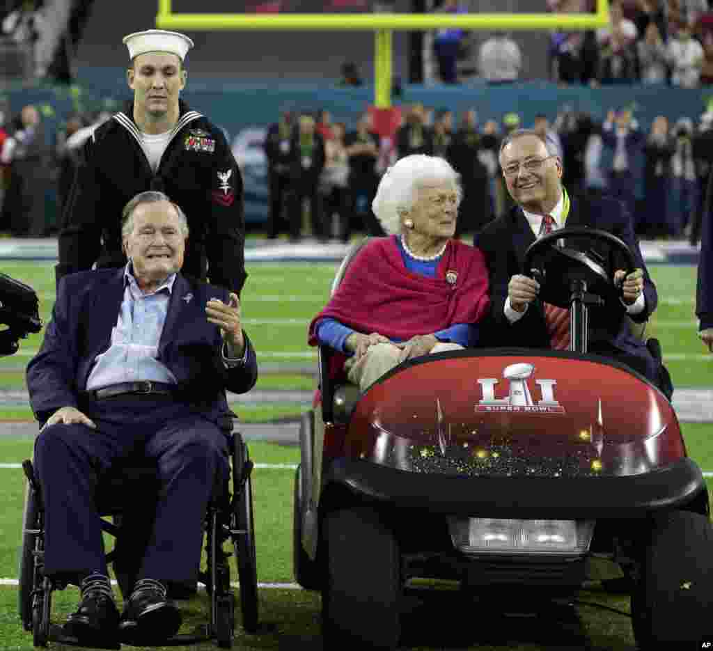 Former President George H.W. Bush and wife, Barbara, wave as they arrive on the field for a coin toss before the NFL Super Bowl 51 football game between the Atlanta Falcons and the New England Patriots, Feb. 5, 2017, in Houston.