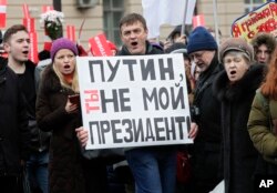 Russia Opposition Protesters shout slogans during a rally holding a poster reading 'Putin, you are not my President', in St.Petersburg, Russia, Sunday, Jan. 28, 2018