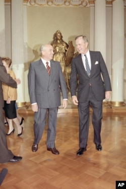 Soviet Presidential Mikhail Gorbachev and U.S. President George Bush are shown where to stand to pose for a photograph, Sunday, Sept. 9, 1990 in Helsinki. In the background is the statue Lex. (AP Photo/Greg Gibson)