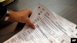Tax professional and tax preparation firm owner Alicia Utley reaches for hard copies of tax forms at the start of the tax season rush in her offices in Boulder, Colo., Jan. 14, 2017.