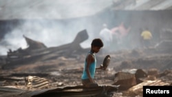  A boy searches for useful items among the ashes of burnt down dwellings after a fire destroyed shelters at a camp for internally displaced Rohingya Muslims in Myanmar's western Rakhine State near Sittwe, May 3, 2016.