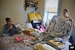 Saturnina Plasencia, 43, folds laundry while talking with her daughter, Ciara, 10, as her newborn, Chloe, sleeps near a window at their home in New York on Monday, Oct. 1, 2018.(AP Photo/Bebeto Matthews)