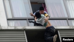 A police officer grabs a man who tries to jump off the 7th floor of a hotel in Chengdu, China. (May 2014)