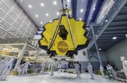 In this April 13, 2017 photo provided by NASA, technicians lift the mirror of the James Webb Space Telescope using a crane at the Goddard Space Flight Center in Greenbelt, Md. (Laura Betz/NASA via AP)