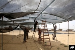 People set up a large tent in preparation for mass demonstrations along the Gaza strip border with Israel, east of Khan Younis, Thursday, March 29, 2018. (AP Photo/Adel Hana)