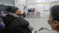 Immigrant worker Blanca Cedillos, center, who is a nanny, glances over at cleaning lady Graciela Uraga, as they watch the presidential inauguration from the Workers Justice Center, a center that supports immigrant workers rights, Wednesday, Jan. 20, 2021