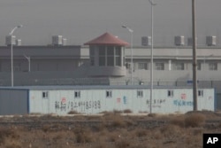 In this Monday, Dec. 3, 2018, photo, a guard tower and barbed wire fences are seen around a facility in the Kunshan Industrial Park in Artux in western China's Xinjiang region. (AP Photo/Ng Han Guan)