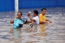 People wade through a flooded road following heavy rainfall in Zhengzhou, Henan province, China July 22, 2021.
