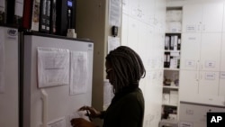Pharmacist Mary Chindanyika looks at documents on a fridge containing a trial vaccine against HIV on the outskirts of Cape Town, South Africa, Wednesday, Nov. 30, 2016. (AP Photo/Schalk van Zuydam)