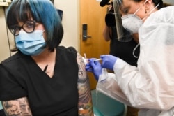 FILE - Nurse Kathe Olmstead, right, gives volunteer Melissa Harting, of Harpersville, N.Y. an injection as the world's biggest study of a possible COVID-19 vaccine, developed by the National Institutes of Health and Moderna Inc., gets underway Monday, July 27, 2020.