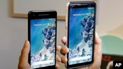 A woman holds up the Google Pixel 2 phone, left, next to the Pixel 2 XL phone at a Google event at the SFJAZZ Center in San Francisco, Wednesday, Oct. 4, 2017. (AP Photo/Jeff Chiu)