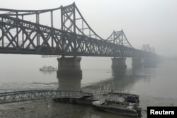 Trucks move across the bridge linking North Korea with the Chinese border city of Dandong in this March 3, 2016 file photo.