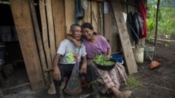 Newlyweds Rosario Cal, 67, and Santiago Suc Lem, 70, pose for a photo while cleaning the greens of a legume known as chipilin, outside their home in the makeshift settlement Nuevo Queja, Guatemala, Sunday, July 11, 2021. (AP Photo/Rodrigo Abd)