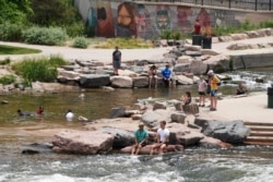 People cool off in the water at the confluence of the South Platte River and Cherry Creek in Denver, Wednesday June 16, 2021. A heat wave continues to hover over the western U.S., pushing the temperature to 99 degrees in Denver. (AP Photo/Brittany Peterso