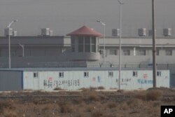 In this Monday, Dec. 3, 2018, photo, a guard tower and barbed wire fences are seen around a facility in the Kunshan Industrial Park in Artux in western China's Xinjiang region. This is one of a growing number of internment camps in Xinjiang.